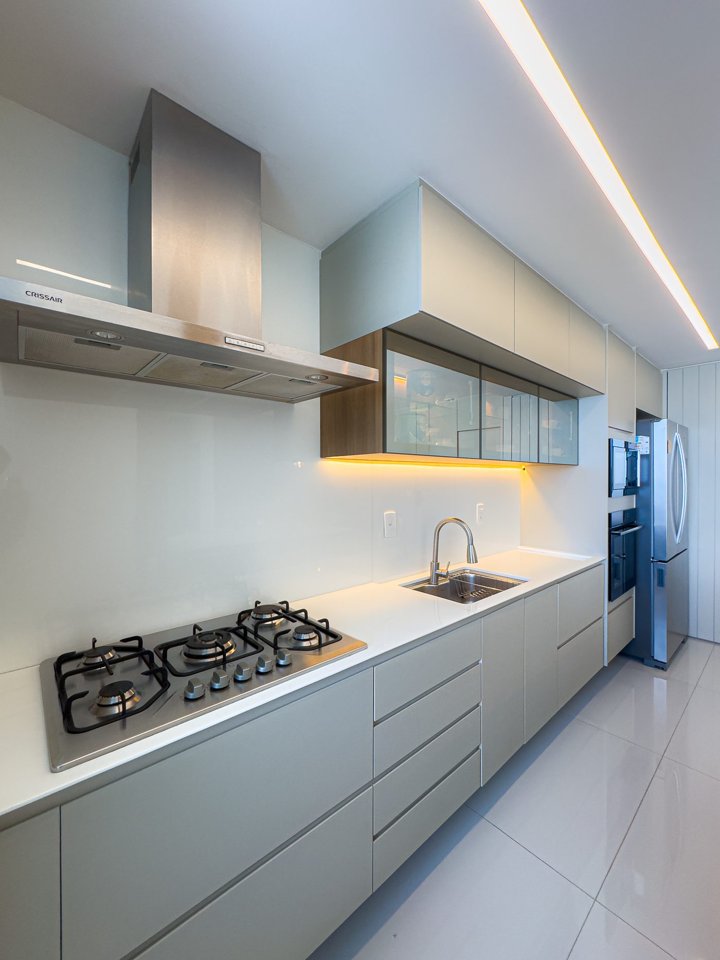 Bancada da cozinha com cooktop, coifa e armários claros