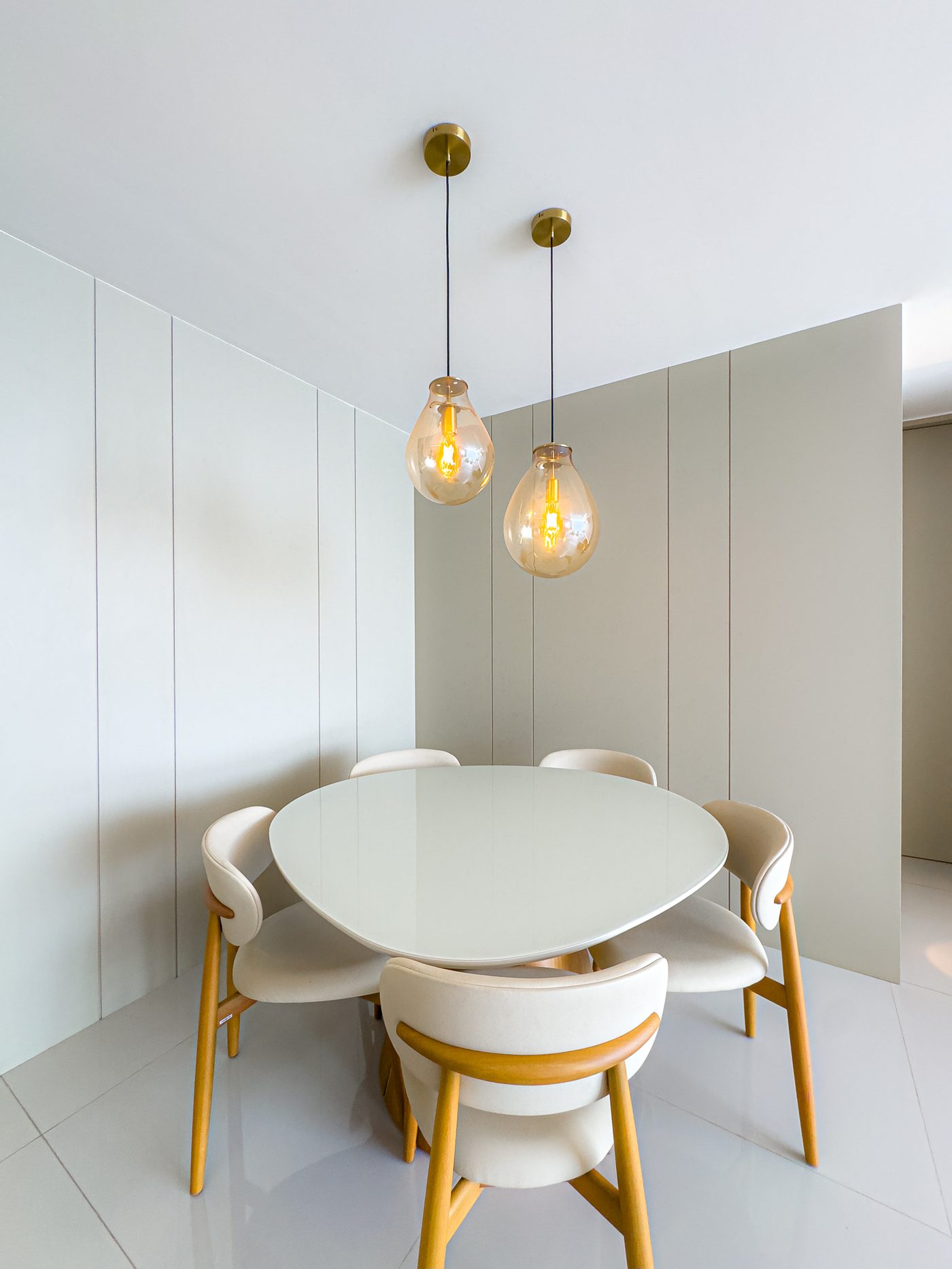 Sala de jantar com mesa oval e pendentes de vidro âmbar